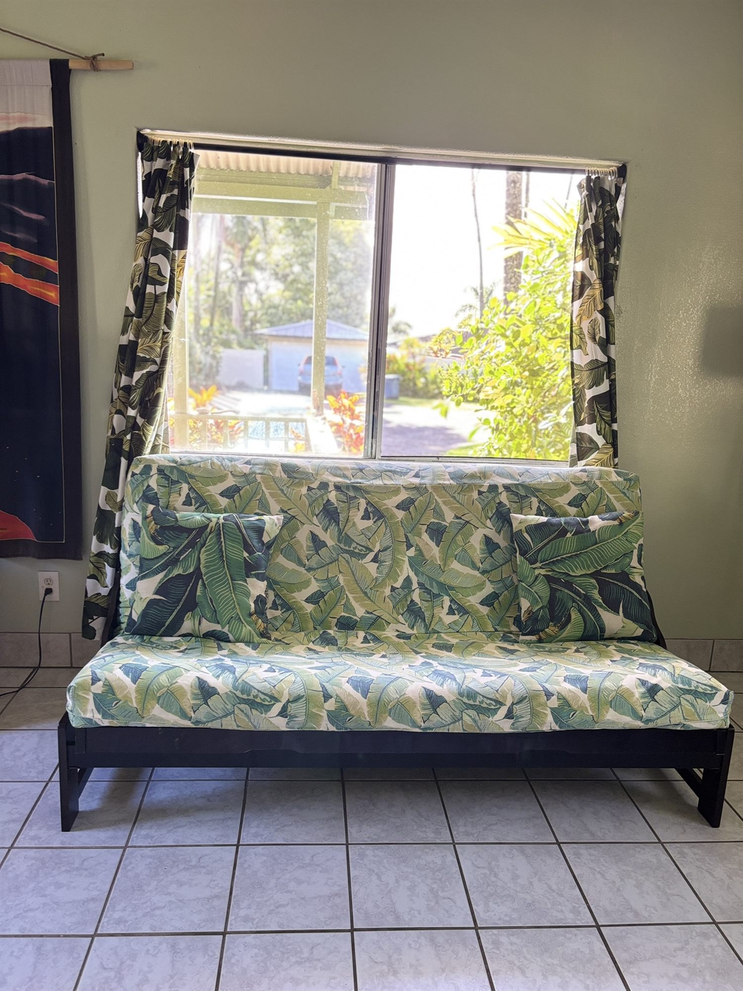 Queen futon in palm-leaf print beneath the front window