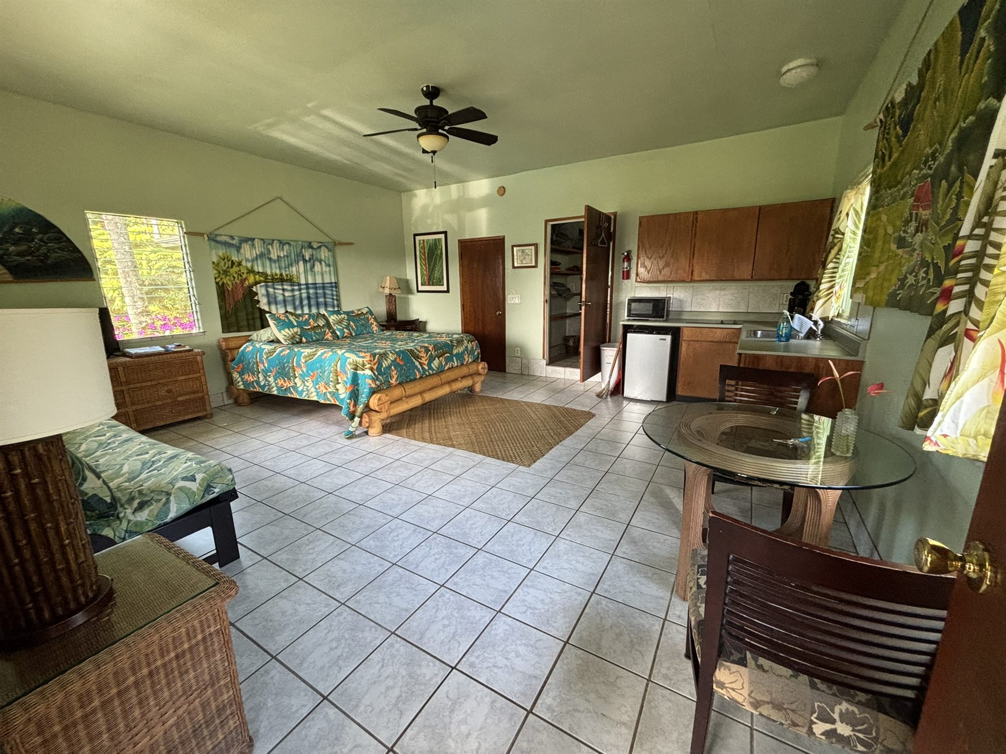 The whole studio in one frame: bed, futon, dining table, and kitchenette